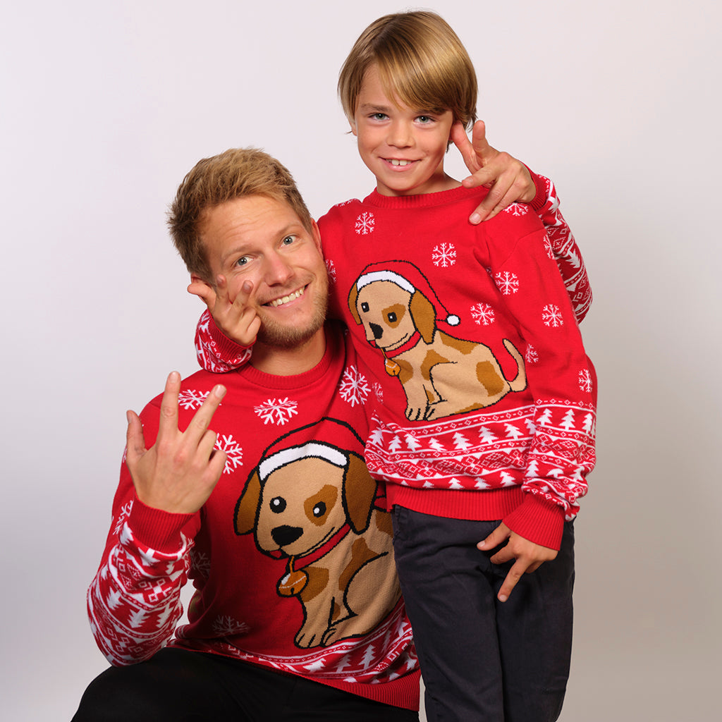 En mand og en dreng iført en rød julesweater med snefnug og en julehund.